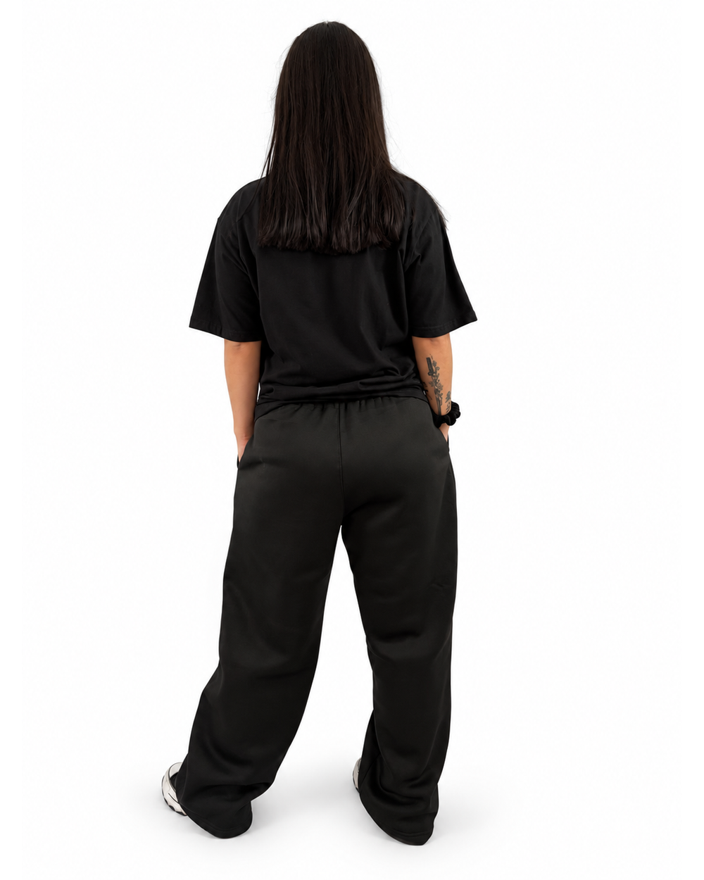 Modelo mujer con outfit NUVA completamente negro, vista posterior.