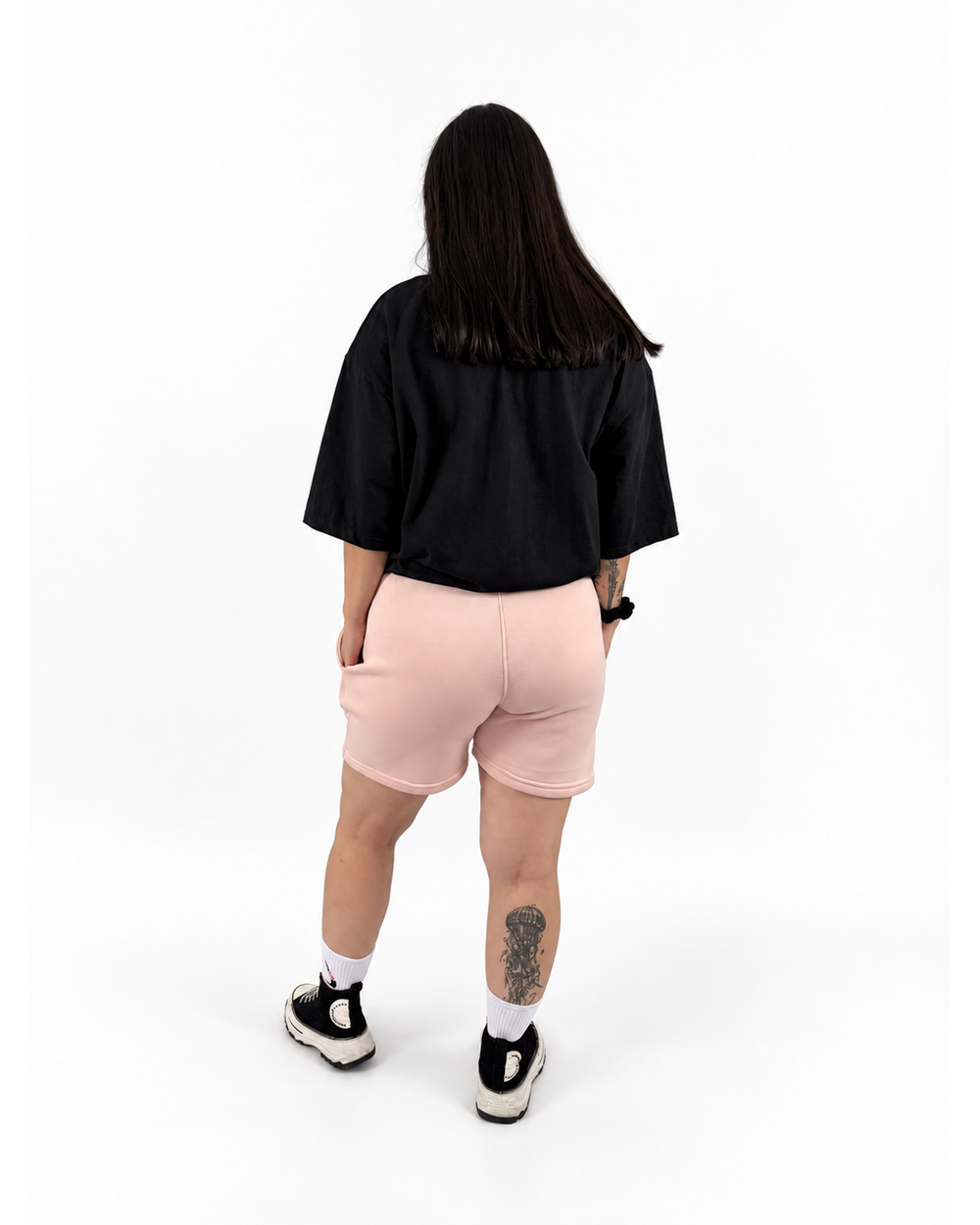 Modelo mujer con playera negra y short rosa NUVA, vista posterior.
