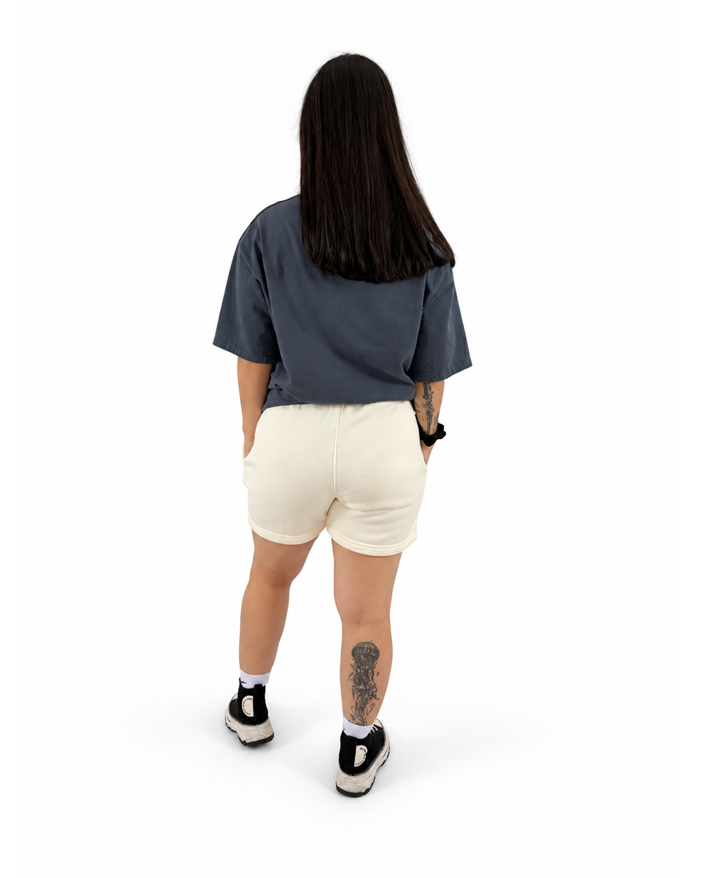 Modelo mujer con playera azul y short amarillo claro NUVA, vista posterior.